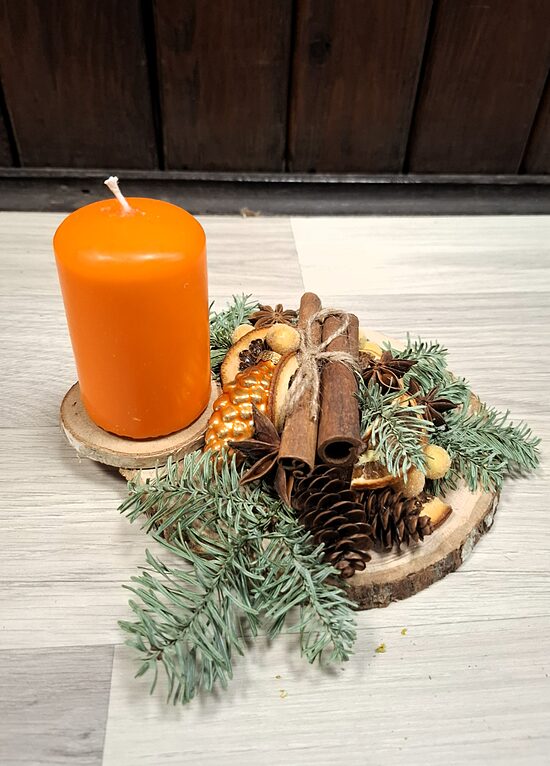 Ziemassvētku kompozīcija ar oranžu sveci, kanēli un dabas materiāliem